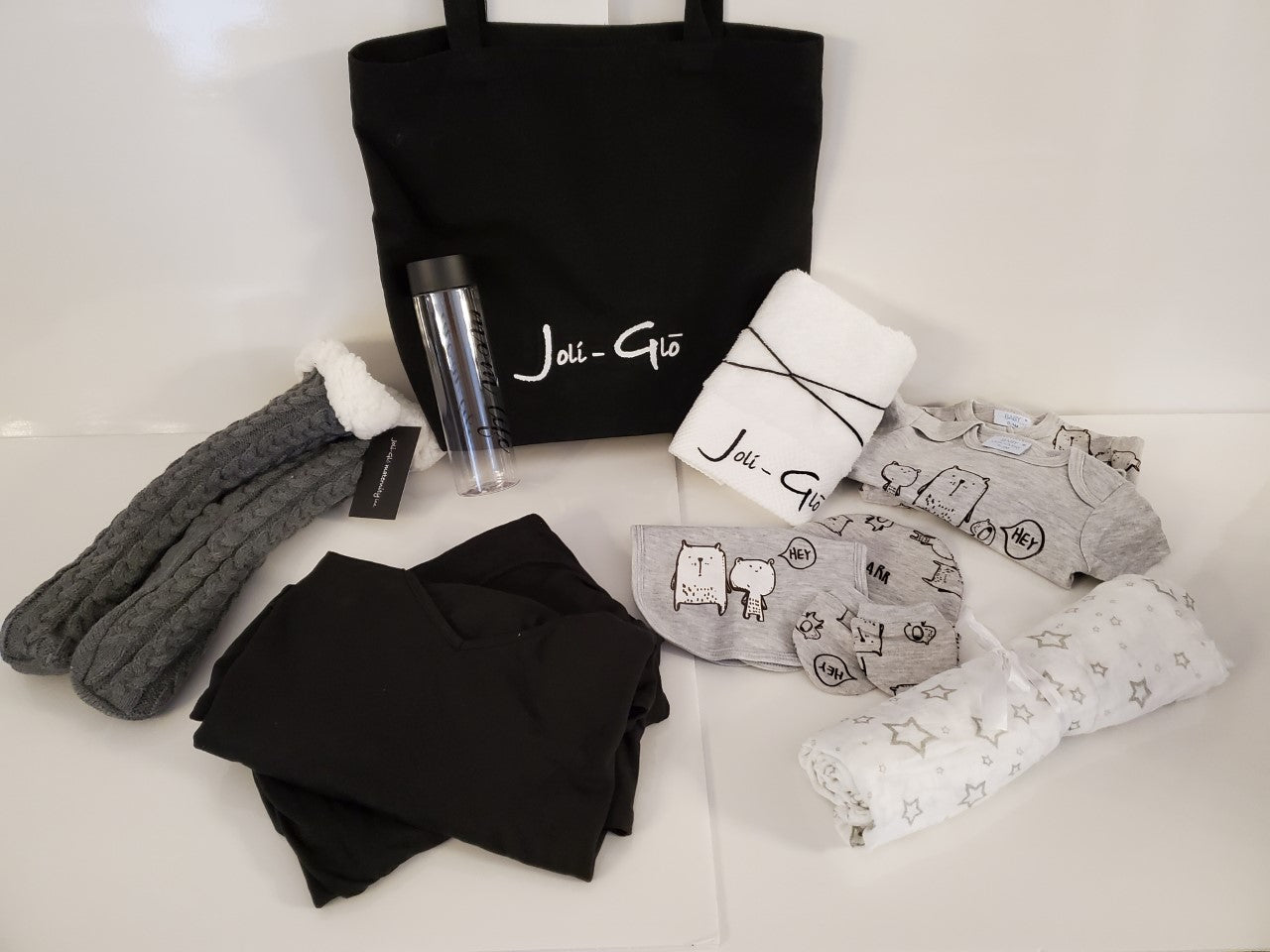 Mom-to-be hospital Bag gift set - includes black canvas tote bag, cotton towel, grey knit slipper socks, grey 5 piece unisex baby pajama set, a white/grey stars bamboo muslin swaddle blanket, "mom life" plastic water bottle and a women's black loungeset